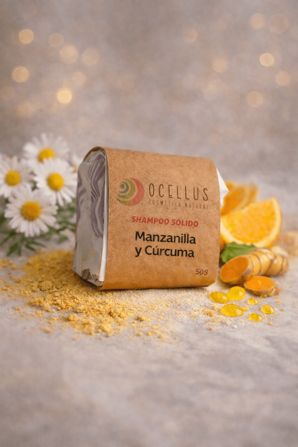 Shampoo sólido Ocellus de manzanilla y cúrcuma rodeado de flores, naranjas y raíz de cúrcuma.
